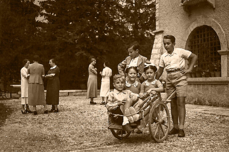 Le gemelle con amici di famiglia, giocano su un piccolo carretto di legno, a Verona nel 1936